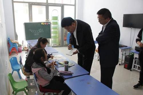 图为北镇市委副书记赵春刚和锦州市残联副理事长孟军询问残疾儿童的学习生活情况