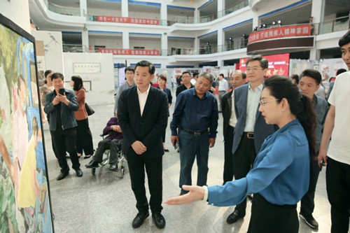 图为市残联副理事长冯俐向省残联和鞍山市委领导介绍我市残疾人作品