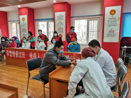 图为志愿者为残疾人及医护人员进行义诊、按摩