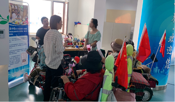 图为残疾人观摩手工编织项目现场展示