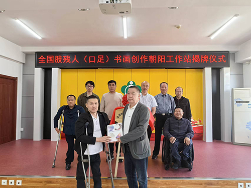 图为中肢协（口足）书画委员会向朝阳市肢协赠送作品集